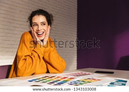 Cheerful artistic woman choosing paint color on a palette indoors