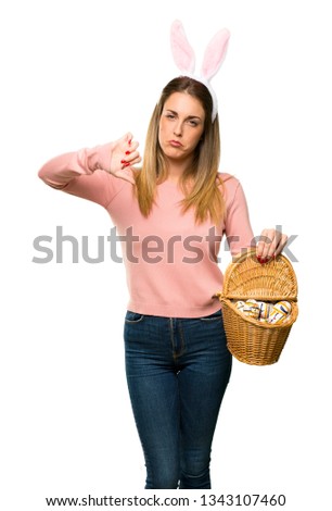 Young woman wearing bunny ears for Easter holidays showing thumb down sign with negative expression on isolated white background