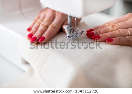 Professional dressmaker using sewing machine, close up