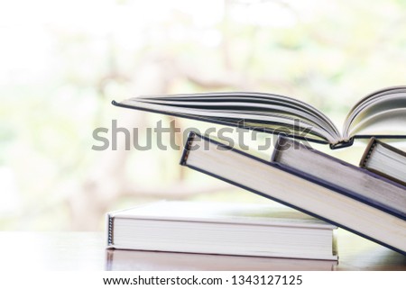 stack of books on a wooden desk with tree background