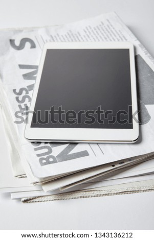 digital tablet with blank screen on business newspapers on white 