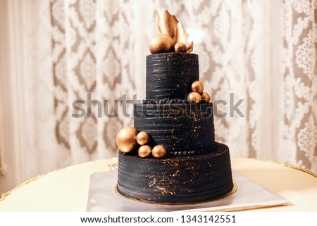 black wedding cake with gold decorations stands on the table, black wedding style Royalty-Free Stock Photo #1343142551