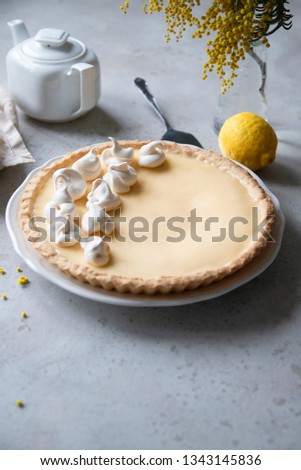 Traditional lemon tart with curd filling decorated with meringues. Top view. Mimosa flowers on background. 