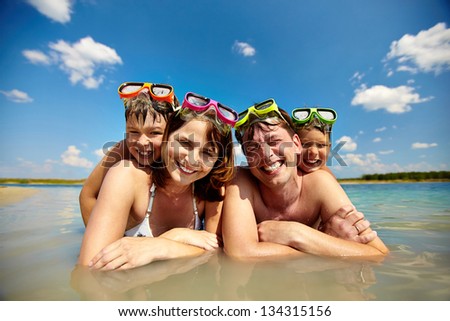 Photo of happy family of divers in water looking at camera