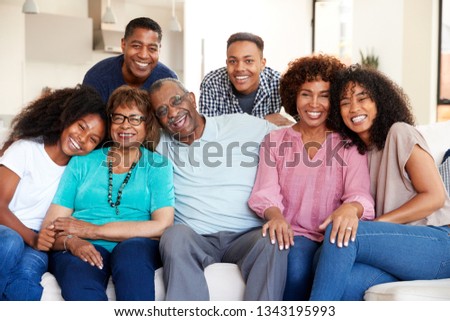 Multi generation black family sitting at home smiling to camera Royalty-Free Stock Photo #1343195993