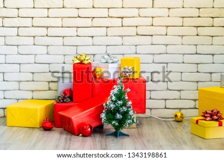There are many gifts and Christmas decoration place on the floor with copy space of white brick