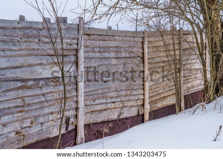 fence around the garden of unpainted boards on a winter day
