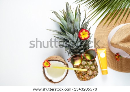 Summer mood concept. Tropical background, ripe organic pinapple face with leafy crown, hipster sunglasses cracked coconut w/ milk and straw, broad brim hat. Flat lay, top view, copy space, isolated.