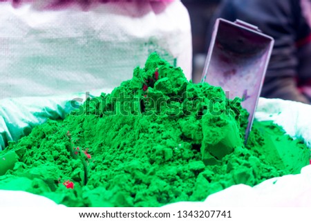 Green gulal powder placed in a pile with a steel iron scoop to measure the quantities for customers.  Sold during the hindu festival of holi these make the festival of colors