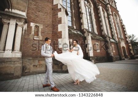 Amazing smiling wedding couple. Pretty bride and stylish groom near the church