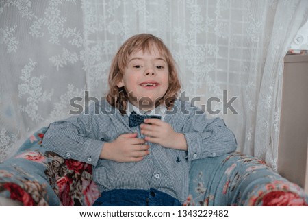 A little boy plays in the phone, looks cartoon. Children at home.