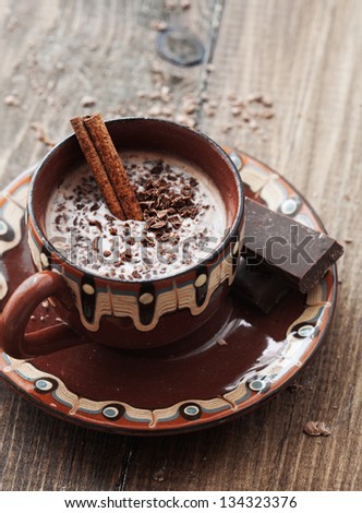 Cup of hot chocolate cocoa with cinnamon sticks on vintage wooden background, selective focus
