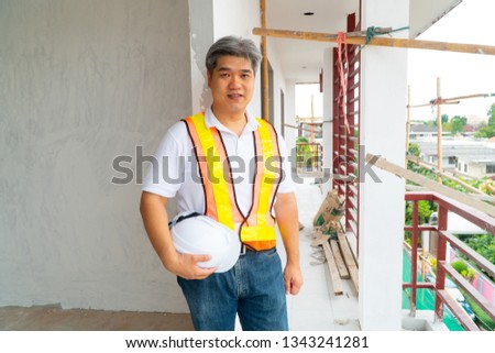 Asian professional engineer workering in house construction site for inspection of the cottage under construction