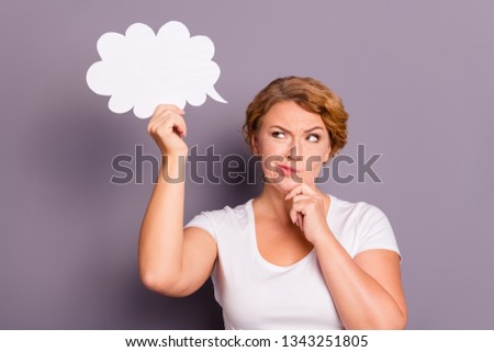 Portrait of nice attractive sad wavy-haired lady in casual white t-shirt holding in hand cloud figure thinking creating solution isolated on gray violet purple pastel background