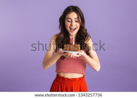 Image of beautiful young pretty woman posing isolated over purple background wall holding holiday cake.