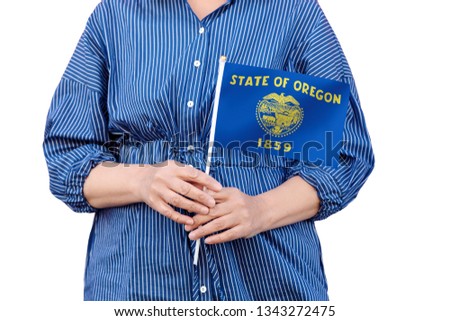 Oregon state flag. Close up of woman's hands holding flag of Oregon isolated on white background.
