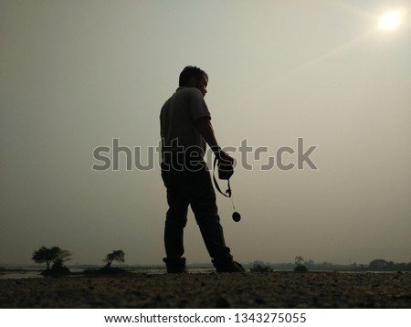 The male photographer is standing holding the camera and is shooting backlit images. By using natural light