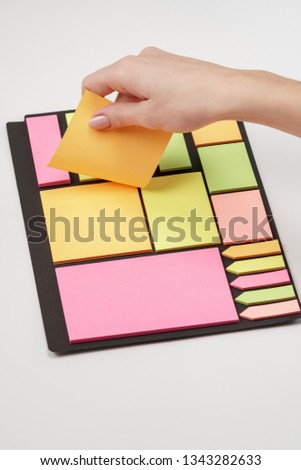 Blank note paper set of different colours forms and sizes. Sticky notes collection on black background. Female hand tear off paper note. Royalty-Free Stock Photo #1343282633