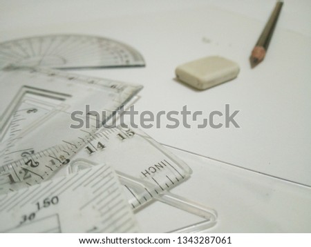 Drafting tool, eraser and pencil are on white background.