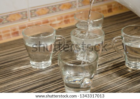 Pouring hot water into transparent glass cups from teapot. Do not be thirsty. Drinking tea with a company.