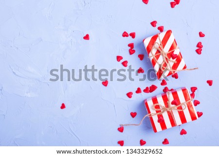 Wrapped gift boxes with presents   and litle red hearts on blue textured background. Selective focus. Place for text. Top view.
