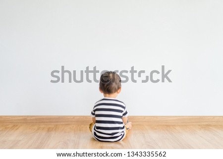 Back view of Little baby boy sitting alone and watching smartphone.