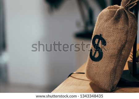 Money bag with dollar sign standing on wooden table
