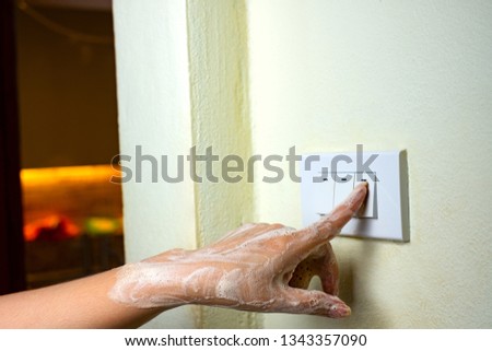 Wet hand turn on lights electric switch on white wall background, Do not turn the power off while moist hands may electric shock concept