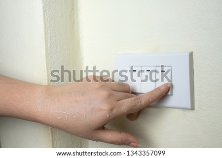 Wet hand turn on lights electric switch on white wall background, Do not turn the power off while moist hands may electric shock concept