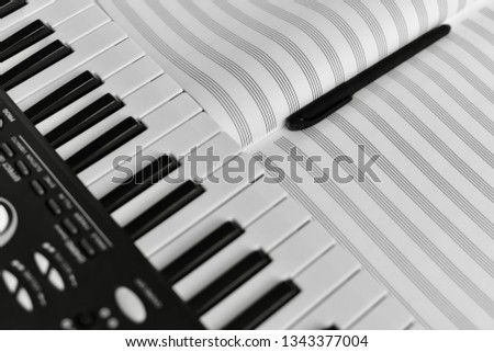 Synthesizer and pages of an open note book with a pencil.
