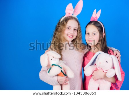 Spread joy and happiness around. Hope love and joyful living. Friends little girls with bunny ears celebrate Easter. Children with bunny toys on blue background. Sisters smiling cute bunny costumes.