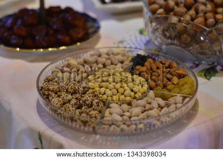 Nuts and candied fruits mix in a woden vintage bowl and on a dark rustic wooden background. close up and selective focus, toned picture 