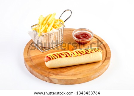 Hot dog with fries and ketchup. Served on a round wooden board. White background.