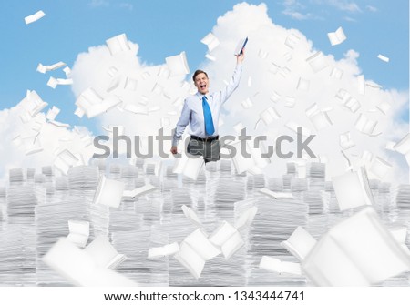 Businessman keeping hand with book up while standing among flying books with cloudly skyscape on background. Mixed media.