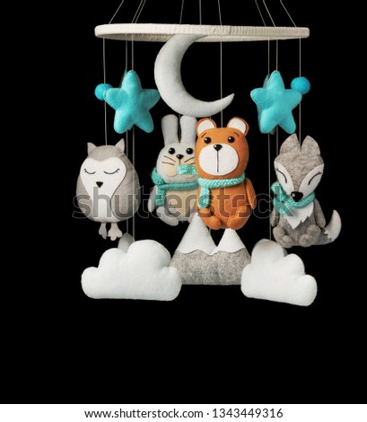 Colorful and eco-friendly children's mobile from felt for children. It consists of bear, fox, owl, rabbit, mountain, stars, clouds and balloons toys. Handmade on black background.