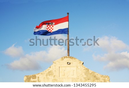 Croatia flag waving on the blue sky on the city Nin Gate.