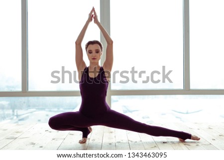 Ordinary wooden floor. Calm and peaceful fit girl showing her stretching exercises while wearing slinky outfit