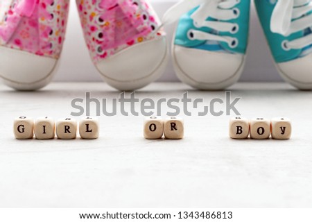 Pink and blue baby booties on a light background. Inscription girl or boy