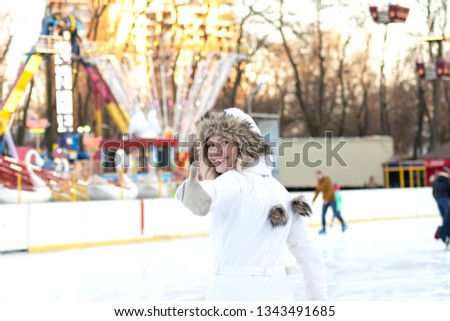beautiful blond girl in a white suit on a ski rink. Charming smiling young woman in a ski suit