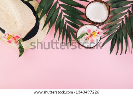 Tropical palm leaves, straw hat and coconut on pink background. Summer concept. Flat lay, top view, copy space