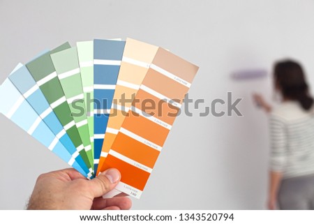 A young woman is looking at a color swatch for painting a room. (Shallow DOF)
