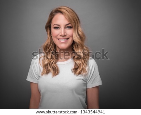 Beautiful blonde is smiling. Studio photo of a young attractive woman on a gray background.