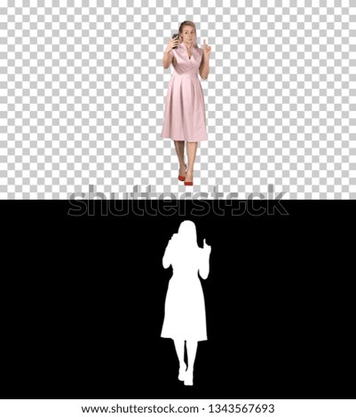 Smiling woman in pink dress doing making video call and walking, Alpha Channel