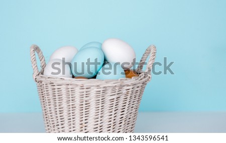 Traditional painted Easter eggs in white basket, pastel color background. Spring and Easter holiday concept.