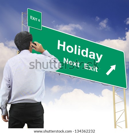 Businessman talking the phone standing in front Road sign concept with the text Holiday