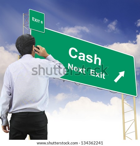 Businessman talking the phone standing in front Road sign concept with the text Cash
