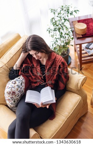 Beautiful young woman reading a book at her home, relaxing and enjoying a nice quiet morning by herself