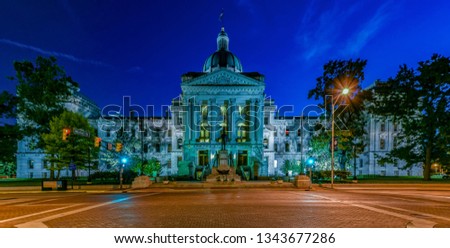 A dramatic view of the Indiana capitol building at night in Indianapolis, with busy streets and a long exposure 
