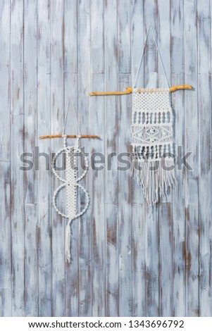 Macrame on a wooden wall. Handmade white thread decor. Decorating a house in a rustic style.