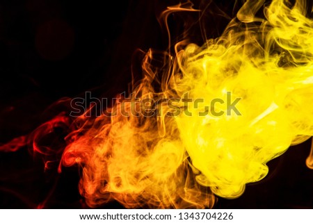 Abstract art colored yellow and orange  smoke on black isolated background. Stop the movement of multicolored smoke on dark background